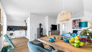 Eine moderne Küche mit Waschmaschine, Herd und Essbereich mit Holztisch und blauen Stühlen.