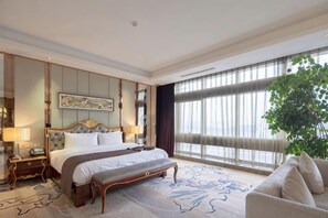A hotel room with a large bed, a bench, a sofa, a large window, and a plant. - Royal Hotel (Chongqing Liangjiang) (Chongqing)