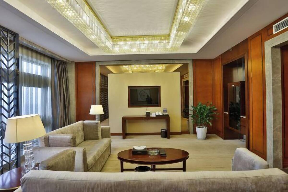 A hotel lobby with a sofa, a coffee table, a console table, a potted plant, and a framed picture on the wall.