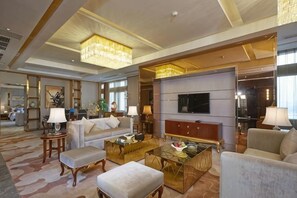 A spacious living room with a large flat-screen TV, comfortable seating, and a chandelier. - Royal Hotel (Chongqing Liangjiang) (Chongqing)