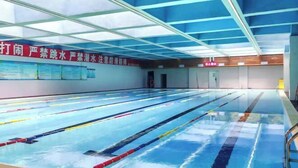 Una piscina interior amb línies de separació clares, un sostre amb panells blaus i cartells informatius a les parets.