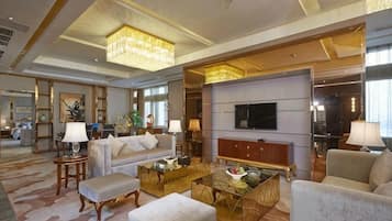 A spacious living area with a large TV, comfortable seating, and a chandelier.
