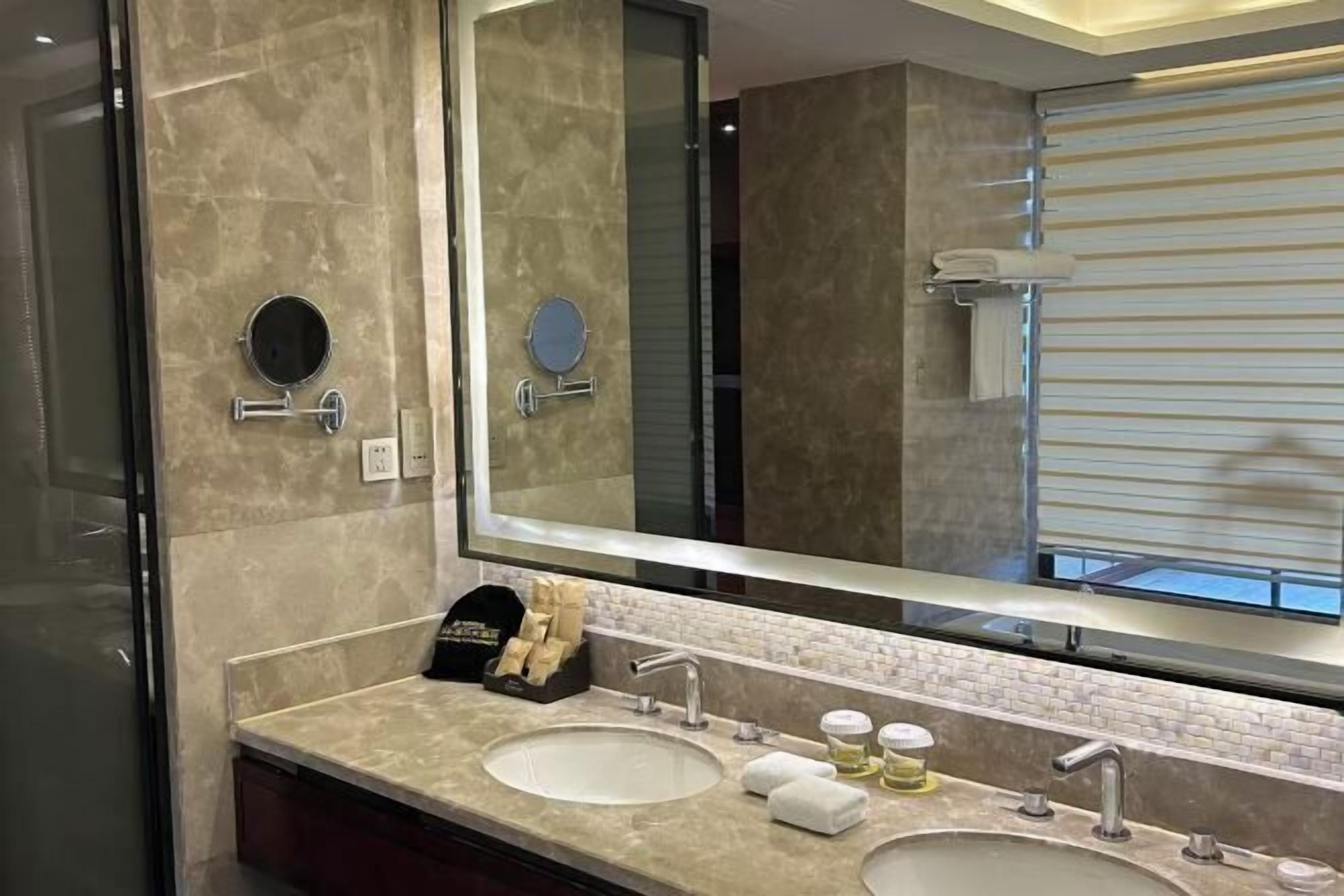 Un baño con dos lavamanos, un espejo grande y un perchero para toallas.