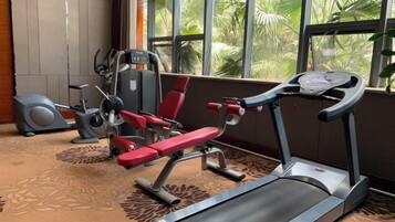 Un gimnasio con equipo de ejercicio, incluyendo una cinta de correr, banco de pesas y bicicleta estática.
