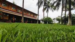 A building with a red and yellow facade, large windows, and a covered porch area. - NuaGoa Nature Retreat Private Limited (Cuttack)