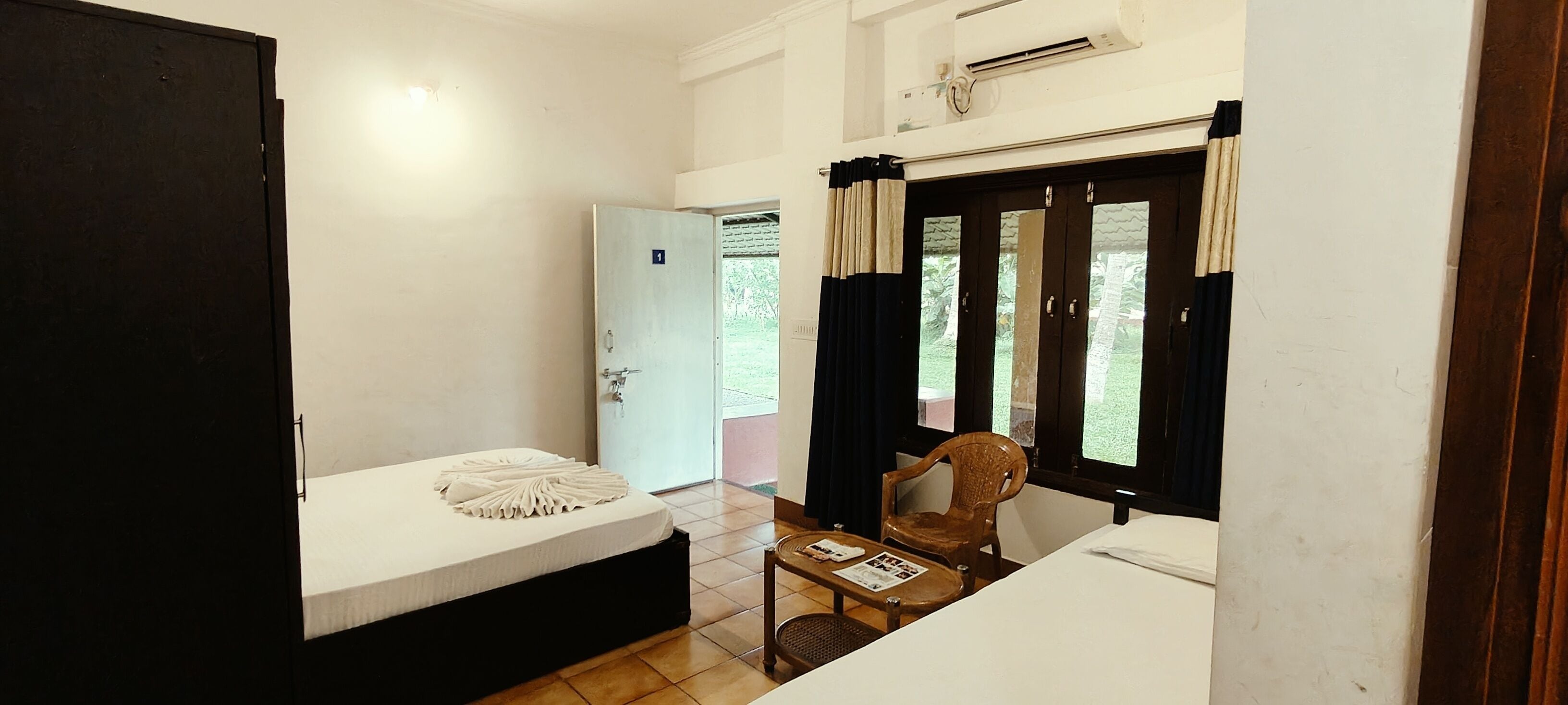 A small, compact room with a bed, a table with a chair, and a window with curtains.