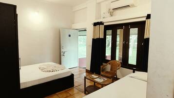 A small, compact room with a bed, a table with a chair, and a window with curtains.