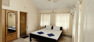 A bedroom with a bed, a wardrobe, a ceiling fan, and curtains.