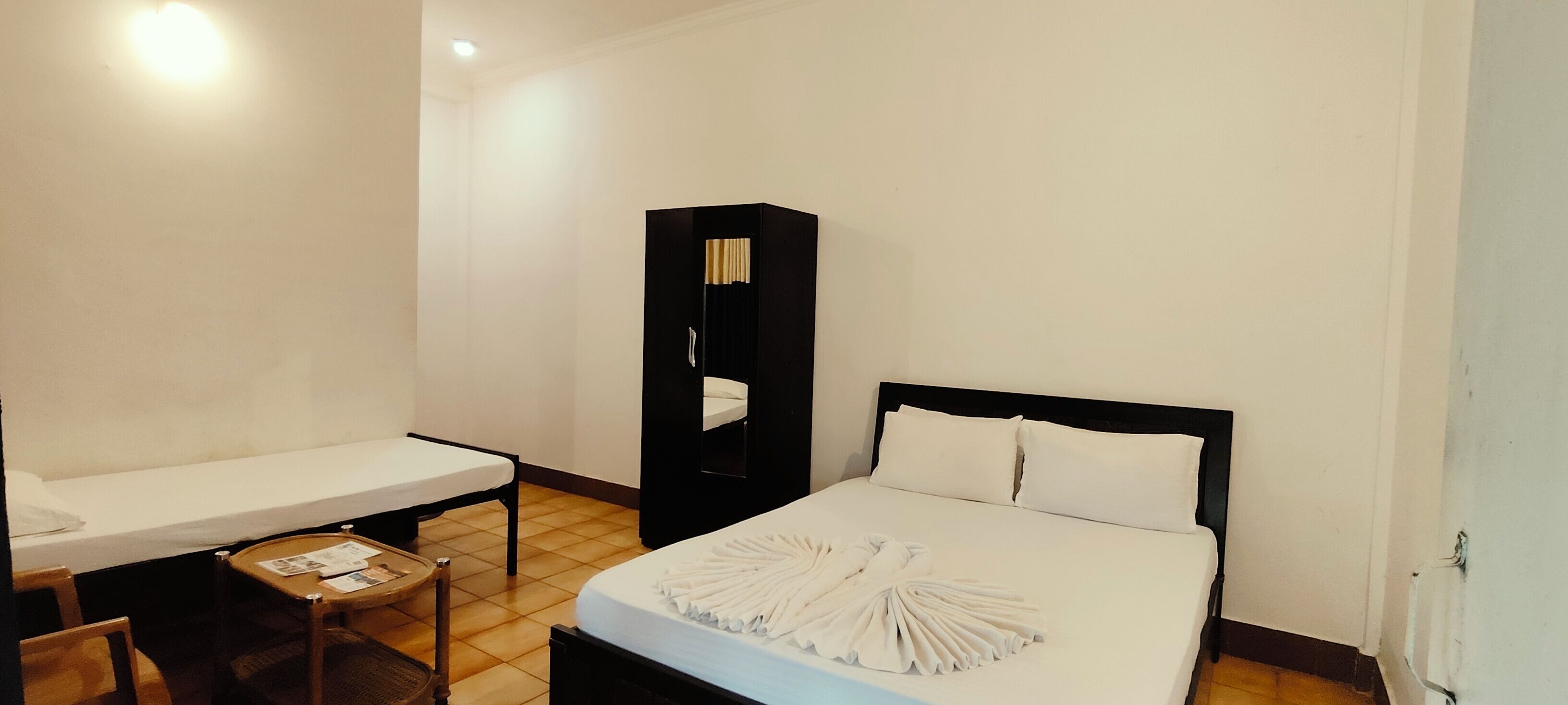 Una habitación de hotel con cama, una mesita, una silla y un armario.