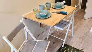 A small dining table with a blue tablecloth, two blue plates, a blue cup, and a pair of scissors. - Tropical Hideaway Studio Apartment (Cardiff)