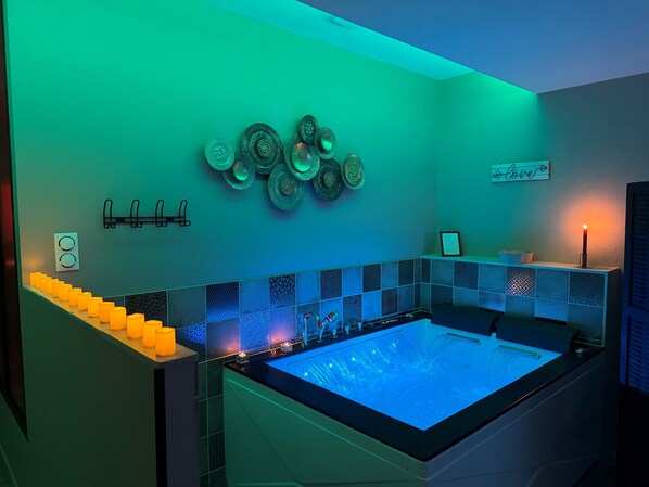 Un baño moderno con una bañera grande, placas decorativas en la pared y una fila de velas.
