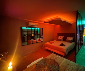 Ein modernes Schlafzimmer mit einem Bett, Nachttischen, einem Spiegel und einer Wand-Klimaanlage.