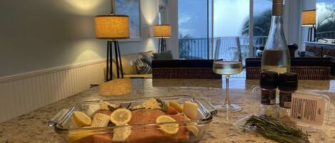 A kitchen counter with a glass dish containing food, a wine glass, and a bottle.