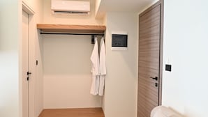 Ein Zimmer mit einem Holzschrank, einem weißen Handtuchhalter, einer kleinen Holzbank und einer weißen Klimaanlage an der Wand.
