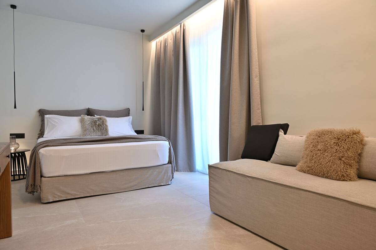 A modern bedroom with a bed, a sofa, and a nightstand.