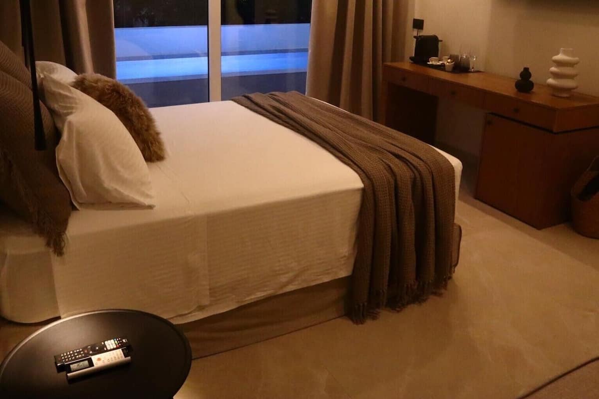A hotel room with a bed, a desk, a TV, and a window with curtains.