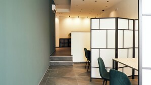 A modern interior with a staircase leading to a seating area with green chairs and a wooden table. - HUB Rooms (Carini)