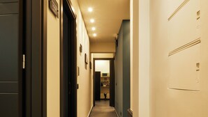 A hotel hallway with doors on both sides, a tiled floor, and recessed lighting. - HUB Rooms (Carini)