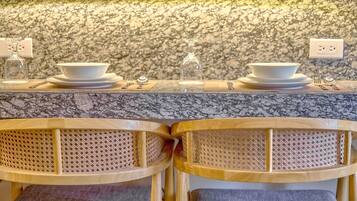 A kitchen counter with two white bowls, a glass, and utensils. The wall has a speckled pattern, and there are two power outlets.