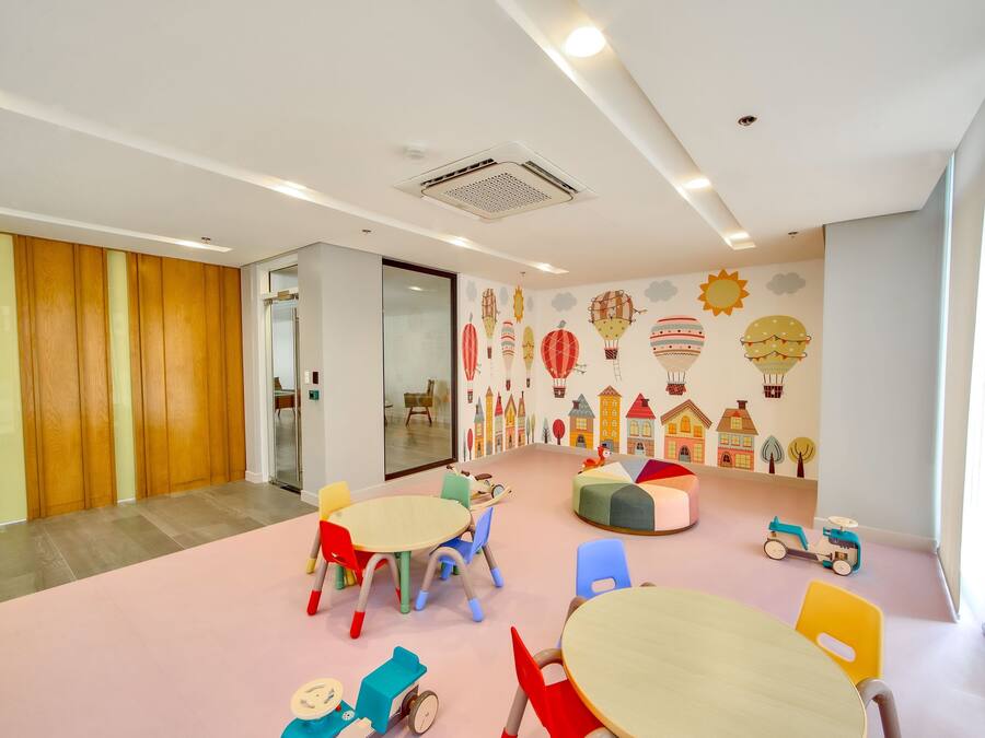 A children's playroom with colorful furniture, a mural with hot air balloons, and a large window.