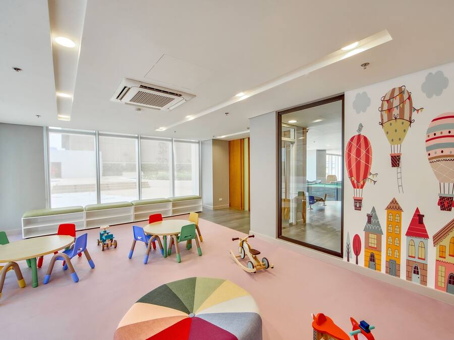 Un salón infantil con sillas, mesas y una alfombra grande y colorida.