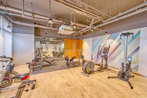 Un gimnasio con equipo de ejercicio diverso, incluyendo bicicletas estáticas y máquinas de pesas, y suelo de madera.