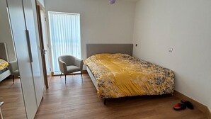 A bedroom with a bed, a chair, a wardrobe, and a ceiling light. - Exquisite Riverside Living in a Stunning Flat (Gravesend)