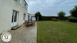 A house with a patio area featuring a table and chairs, a covered outdoor seating area, and a well-maintained lawn.