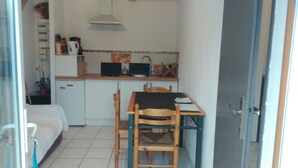 Eine kleine Küche mit Esstisch und Stühlen, einem kleinen Kühlschrank und einer Mikrowelle.