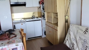 A compact living space with a kitchenette, a dining area, and a sofa with patterned upholstery. - Appartement 6 Couchages 1800m d Altitude (Bagnères-de-Luchon)
