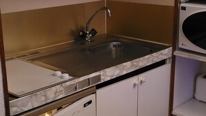 A compact kitchen with a sink, cabinets, and a microwave. - Appartement 6 Couchages 1800m d Altitude (Bagnères-de-Luchon)