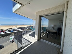 En balkon med udsigt over stranden og parkerede biler.