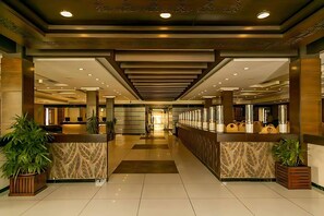 A modern hotel lobby with a central reception desk, seating areas, and a clean, polished floor. - Grand Regency (Islamabad)
