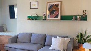 Una sala moderna con un sofá seccional gris, una mesa de centro de madera y un estante verde con objetos decorativos.