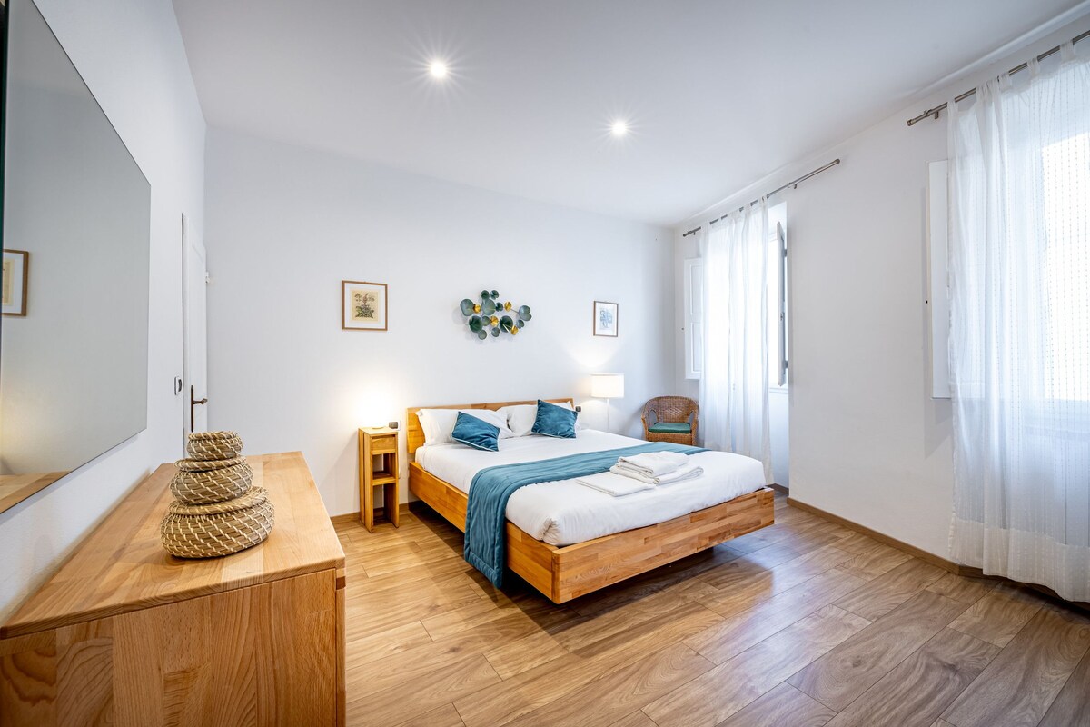 A bedroom with a wooden bed, bedside tables, a mirror, and a wall-mounted decoration.