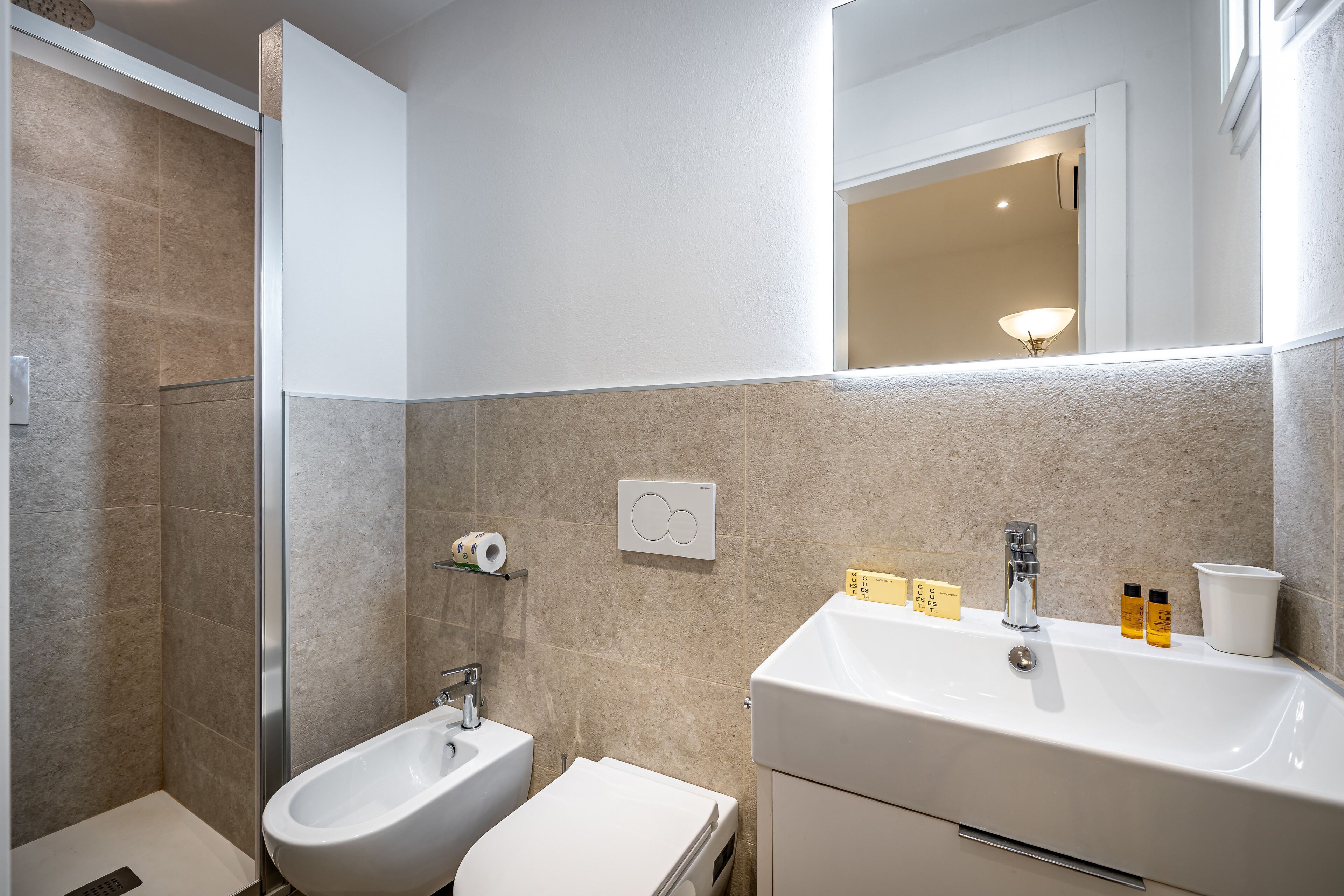 Ein modernes Badezimmer mit einem Bidet, einem Waschbecken und einem Spiegel.
