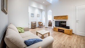A modern living room with a sofa, TV stand, and wooden flooring. - YiD Pilastri (Florence)