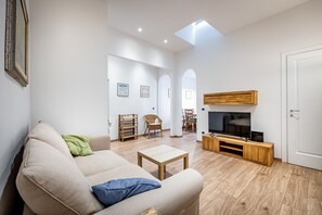 A modern living room with a sofa, TV stand, and wooden flooring. - YiD Pilastri (Florence)