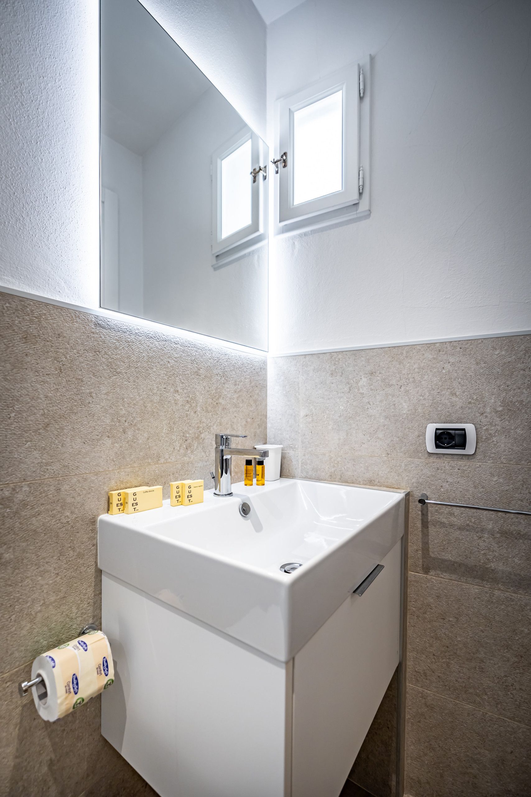 A bathroom with a white sink, a mirror, and a toilet.