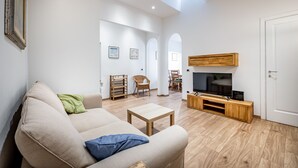 Una sala de estar con un sofá, una mesa de centro, un mueble para televisión y un comedor con sillas y una mesa.