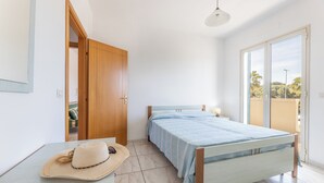 A bedroom with a bed, a wooden wardrobe, a door leading to another room, a table with a hat, and a view through a window. - Apartment Balcony Sea View - Gallipoli (Gallipoli)