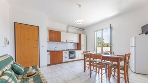 A modern kitchen with white cabinets, a dining table with chairs, and a large window. - Apartment Balcony Sea View - Gallipoli (Gallipoli)
