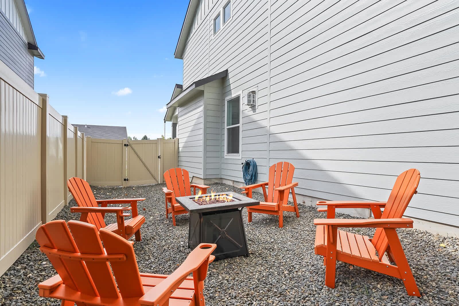 An outdoor patio with orange Adirondack chairs and a fire pit.