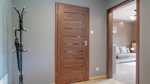 A wooden door with a handle and a coat rack to the left. - RentPlanet - Pogodne Osiedle (Kolobrzeg)