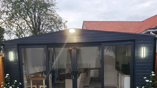 Un bâtiment moderne aux couleurs sombres, doté d’une entrée avec une porte en verre, d’une cuisine visible et d’un paillasson portant le nom « Cillin & Grilluh ».