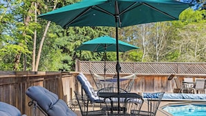 A poolside area with lounge chairs, a table, and umbrellas.