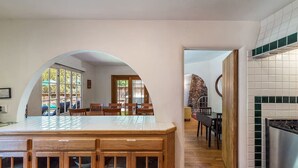 A kitchen with a large island, wooden chairs, and a dining area with a view of the outdoors.