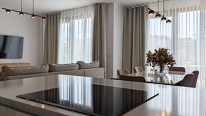 A modern living room with a large island, a sofa, a dining table with chairs, and a TV mounted on the wall. - ASTER sea & spa dúplex (Villajoyosa)