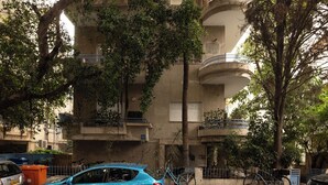 A multi-story building with balconies, trees, and parked bicycles. - Spacious 3BR Penthouse w Rooftop (Tel Aviv)
