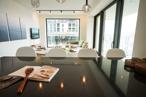 A modern dining area with a large table, chairs, and a view of the cityscape through large windows. - BE OST Vict 25-0202 in Oostende (Ostend)